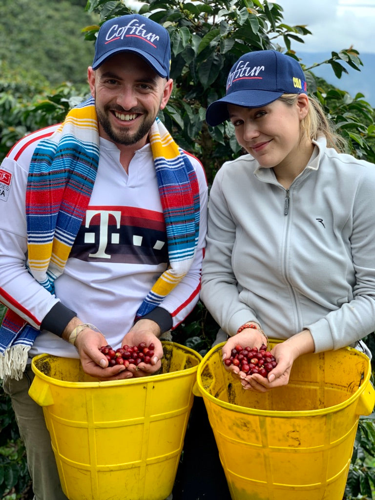 Vera Richartzund Frederic Bertolone von Cofitur zeigen stolz ihre selbst gepflückten Kaffeekirschen auf der Finca in Kolumbien – gelebte Nähe zum Ursprung des Kaffees, Origintrip nach Kolumbien